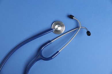 Photo of Stethoscope on blue background, top view. Medical tool