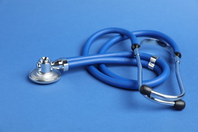 Photo of Stethoscope on blue background, closeup. Medical tool