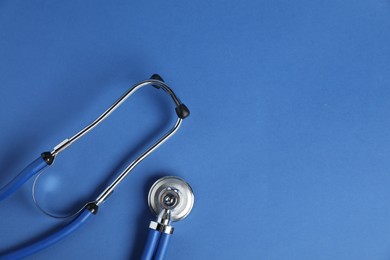 Photo of Stethoscope on blue background, top view. Space for text