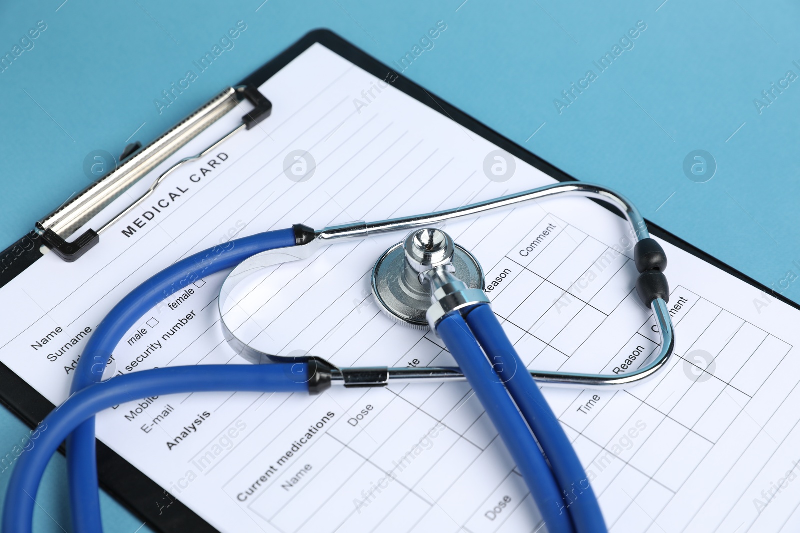 Stethoscope and medical card form on light blue background, closeup Photo of Stethoscope and medical card form on light blue background, closeup