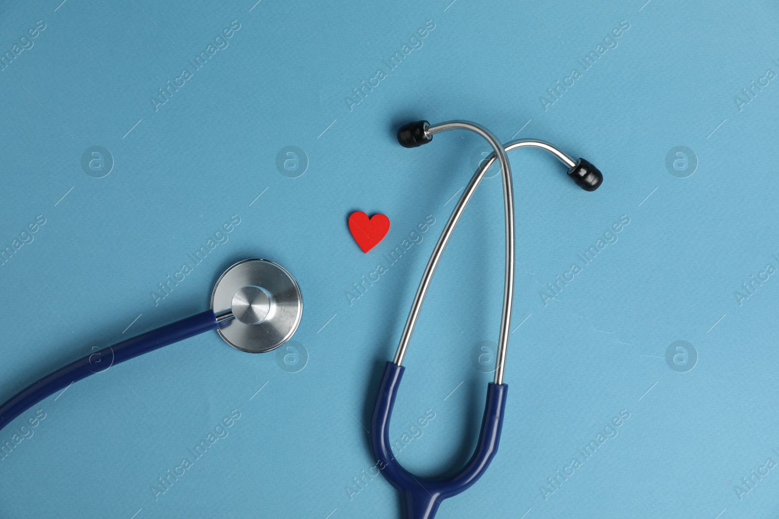 Stethoscope and red decorative heart on light blue background, flat lay Photo of Stethoscope and red decorative heart on light blue background, flat lay