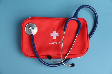 Photo of Stethoscope and first aid kit on blue background, top view