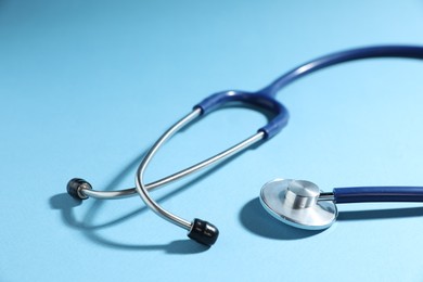 Photo of Stethoscope on light blue background, closeup. Medical tool