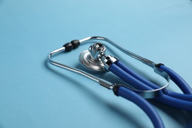 Photo of Stethoscope on light blue background, closeup. Medical tool