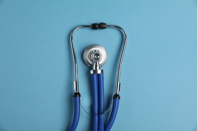 Photo of Stethoscope on light blue background, top view