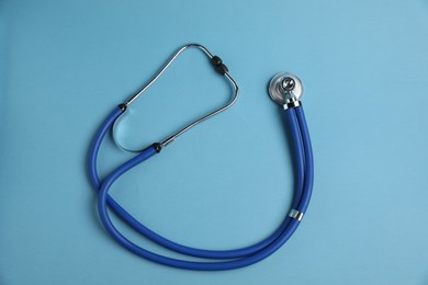 Photo of Stethoscope on light blue background, top view