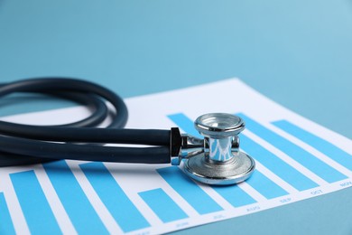 Photo of Stethoscope and chart on light background, closeup