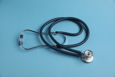 Photo of Stethoscope on light blue background, above view. Medical tool
