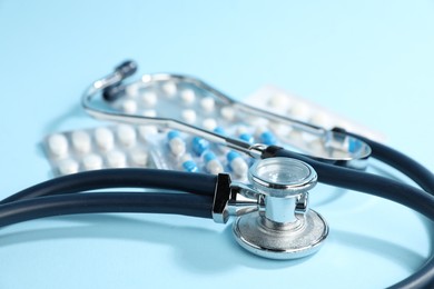 Photo of Stethoscope and pills on light background, closeup