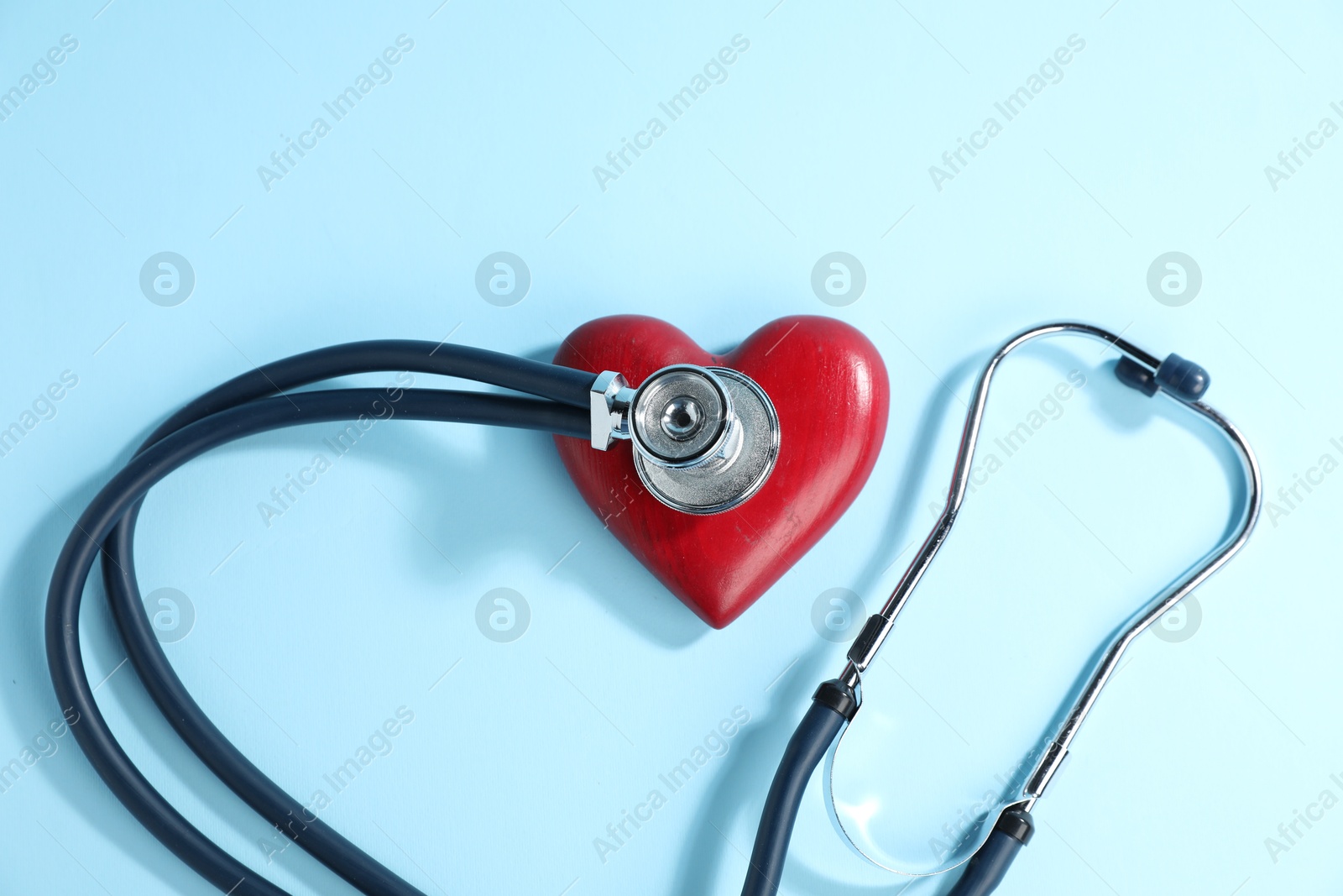 Stethoscope and red decorative heart on light blue background, top view Photo of Stethoscope and red decorative heart on light blue background, top view