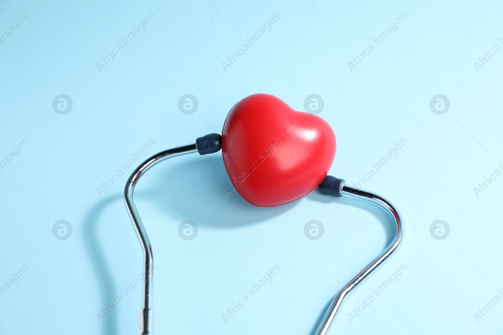 Stethoscope and red decorative heart on light blue background, top view Photo of Stethoscope and red decorative heart on light blue background, top view