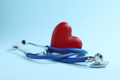 Photo of Stethoscope and red decorative heart on light blue background