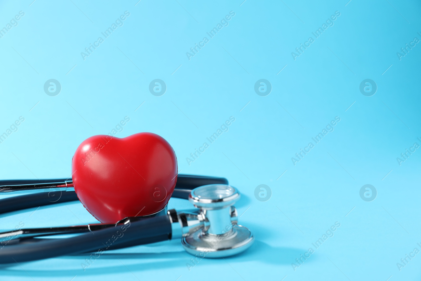 Stethoscope and red decorative heart on light background, closeup. Space for text Photo of Stethoscope and red decorative heart on light background, closeup. Space for text