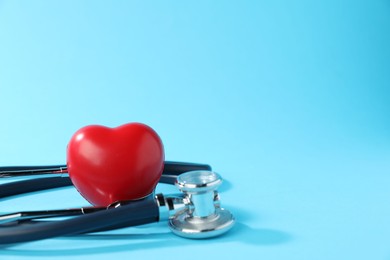 Photo of Stethoscope and red decorative heart on light background, closeup. Space for text