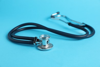 Photo of Stethoscope on light blue background, closeup. Medical tool