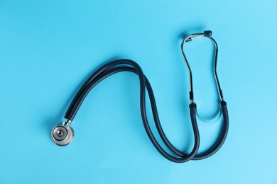 Photo of Stethoscope on light blue background, top view