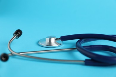 Photo of Stethoscope on light blue background, closeup. Medical tool