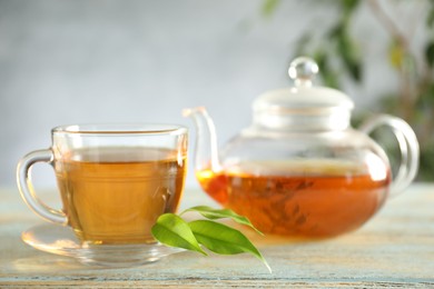 Freshly brewed tea in glass cup and teapot on wooden table