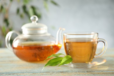 Photo of Freshly brewed tea in glass cup and teapot on wooden table