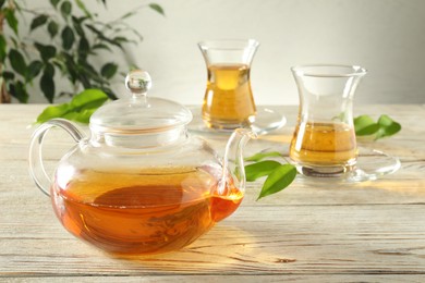 Photo of Freshly brewed tea in glass cups and teapot on wooden table