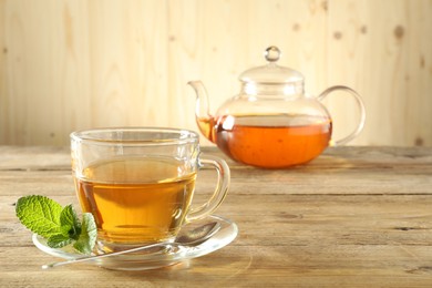 Photo of Freshly brewed tea in glass cup and teapot on wooden table
