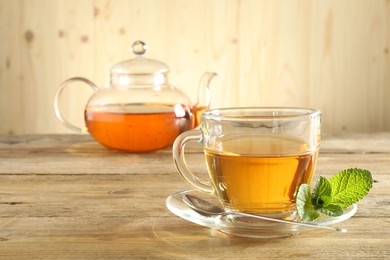 Photo of Freshly brewed tea in glass cup and teapot on wooden table