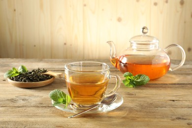 Photo of Freshly brewed tea in glass cup and teapot on wooden table