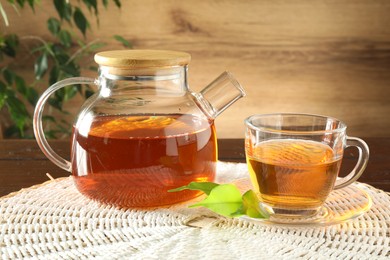 Photo of Freshly brewed tea in glass cup and teapot on table