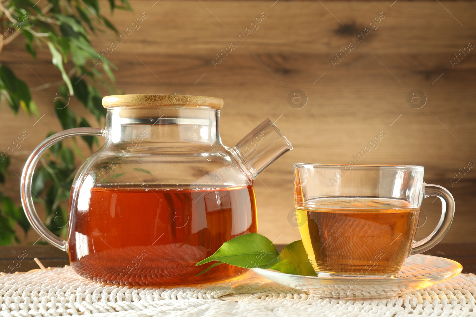 Freshly brewed tea in glass cup and teapot on table Photo of Freshly brewed tea in glass cup and teapot on table