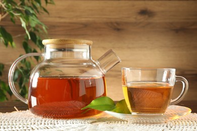 Photo of Freshly brewed tea in glass cup and teapot on table