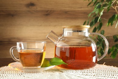 Photo of Freshly brewed tea in glass cup and teapot on table