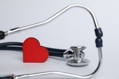 Photo of Stethoscope and red decorative heart on light background, closeup