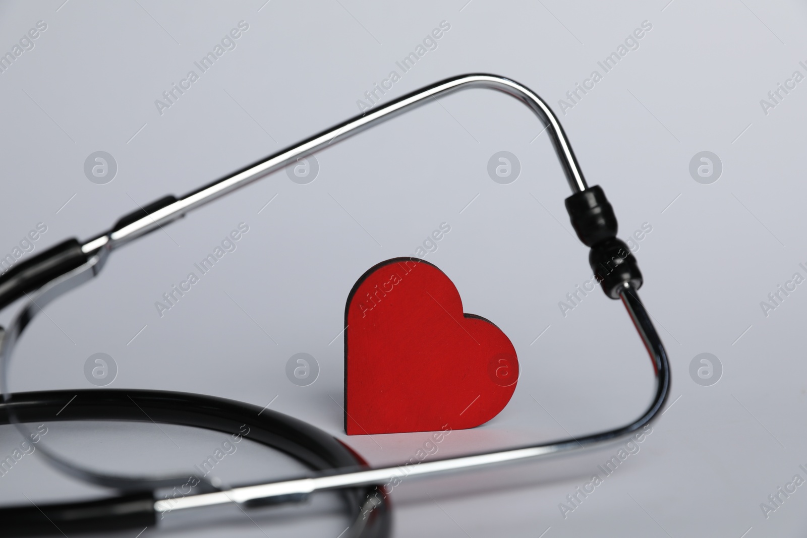 Stethoscope and red decorative heart on light background, closeup Photo of Stethoscope and red decorative heart on light background, closeup
