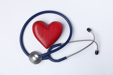 Photo of Stethoscope and red decorative heart on light background, top view