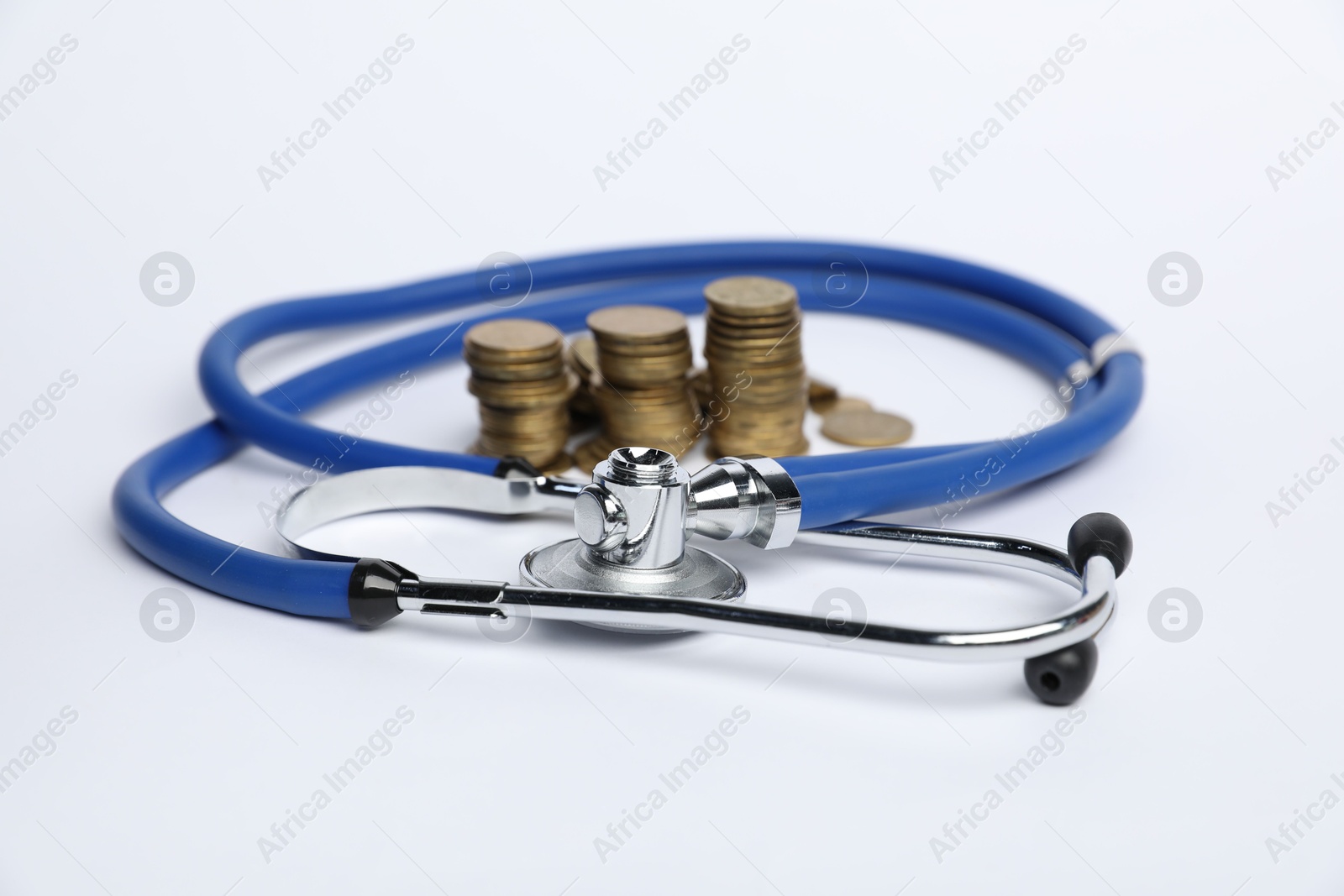 Stethoscope and coins on light background, closeup Photo of Stethoscope and coins on light background, closeup