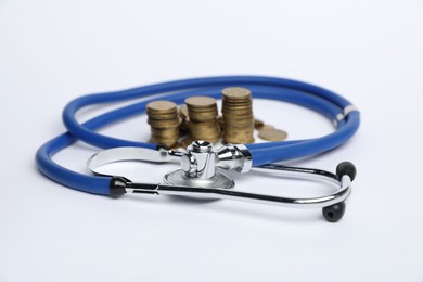 Photo of Stethoscope and coins on light background, closeup