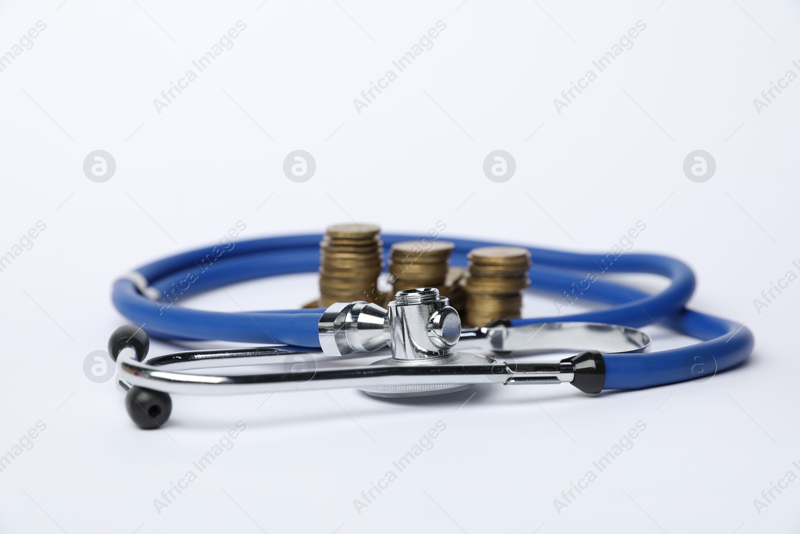 Stethoscope and coins on light background, closeup Photo of Stethoscope and coins on light background, closeup