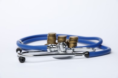 Photo of Stethoscope and coins on light background, closeup