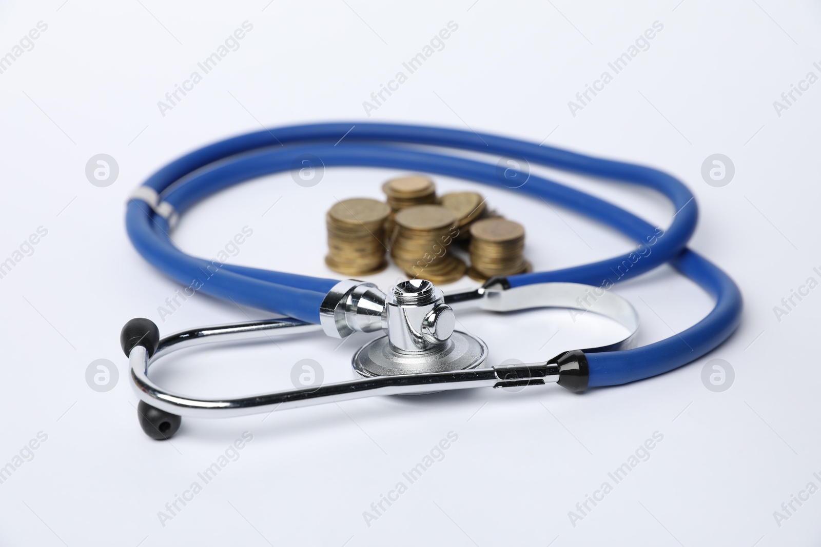 Stethoscope and coins on light background, closeup Photo of Stethoscope and coins on light background, closeup