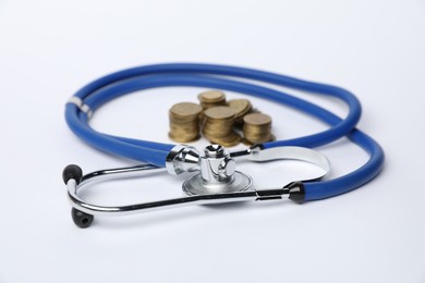 Photo of Stethoscope and coins on light background, closeup