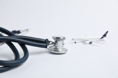 Photo of Stethoscope and airplane model on light background, selective focus