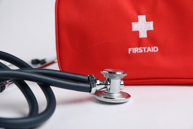 Photo of Stethoscope and first aid kit on light background, closeup