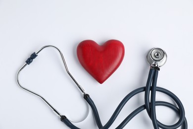 Photo of Stethoscope and red decorative heart on light background, flat lay