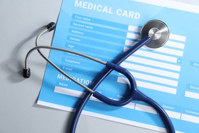 Photo of Stethoscope and medical card form on light background, top view