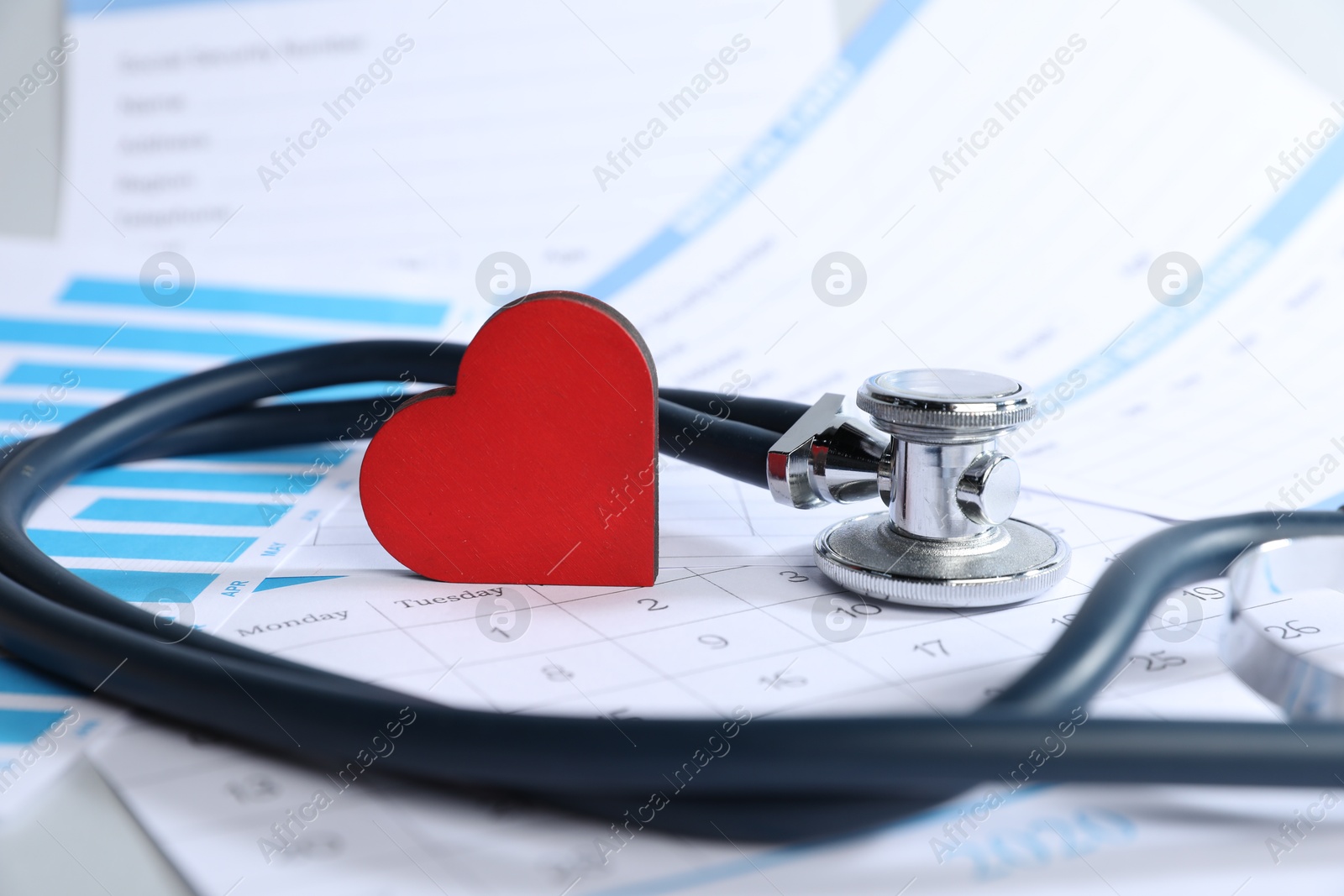 Stethoscope, calendar, chart and medical card forms on table, closeup Photo of Stethoscope, calendar, chart and medical card forms on table, closeup