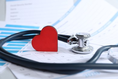 Photo of Stethoscope, calendar, chart and medical card forms on table, closeup