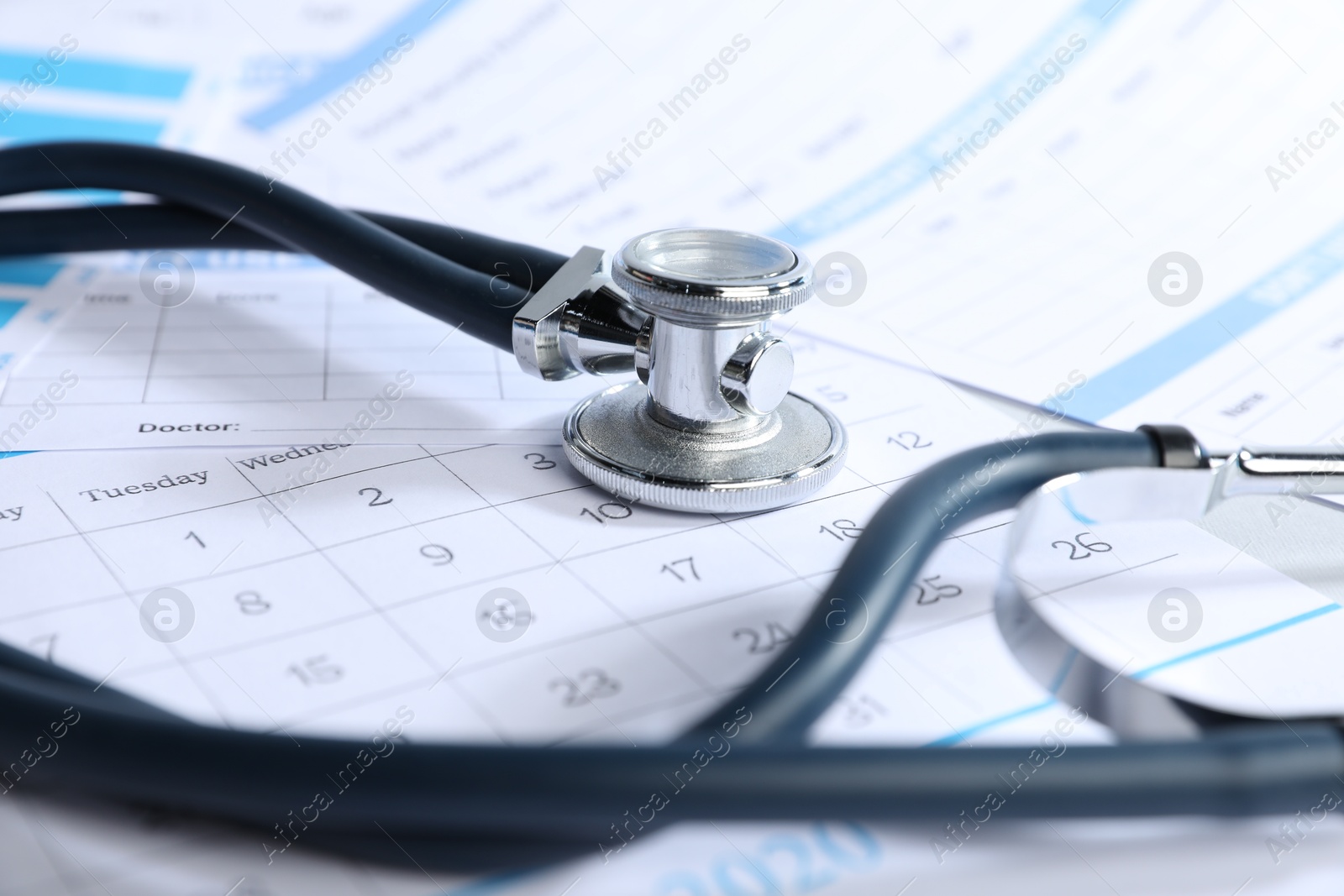 Stethoscope, calendar and medical card forms on table, closeup Photo of Stethoscope, calendar and medical card forms on table, closeup