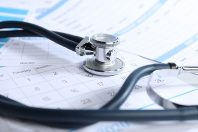 Photo of Stethoscope, calendar and medical card forms on table, closeup