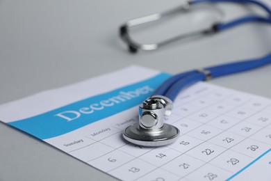 Photo of Stethoscope and calendar on light background, closeup