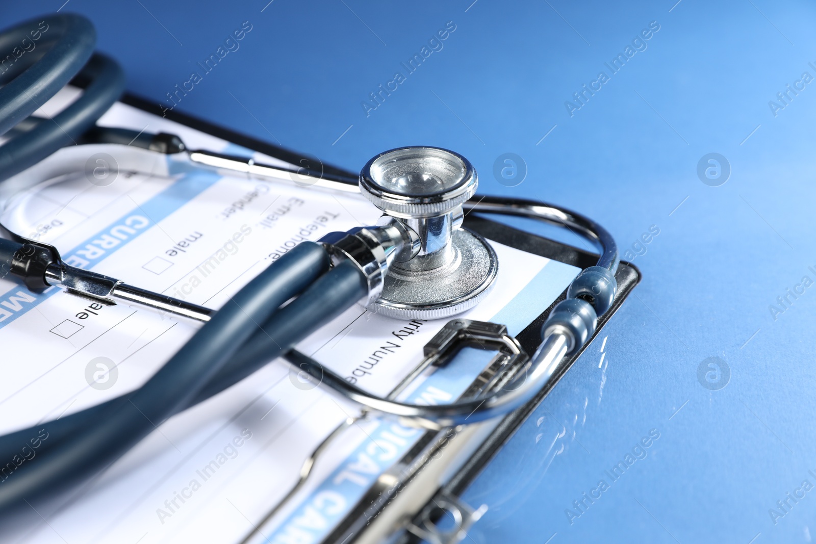 Stethoscope and medical card form on blue background, closeup Photo of Stethoscope and medical card form on blue background, closeup